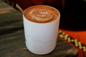 cup of coffee with cream on wooden background