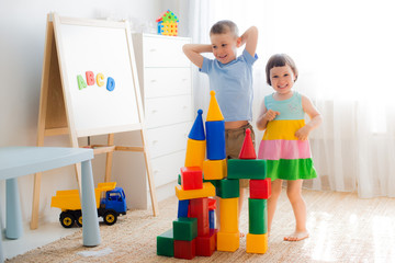 Happy preschool children play with toy blocks.