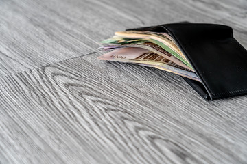 black leather wallet with various curencies in it