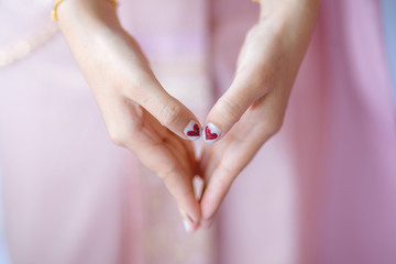 Girl Hands & Heart Symbol with red heart on nails.
