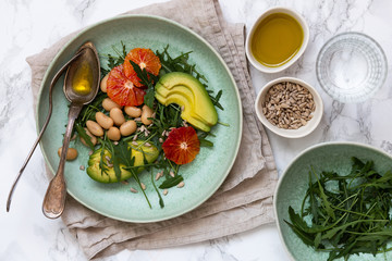 Vegan salad with rucola, seeds, avocado, orange and beans seasoned with olive oil. Healthy eating concept