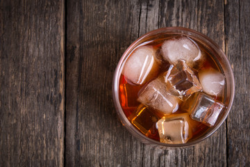 Whiskey with ice on wooden table. Top view with copy space