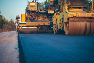 Road works in the city. Working on special equipment cut off the old asphalt on a Sunny summer day - obrazy, fototapety, plakaty