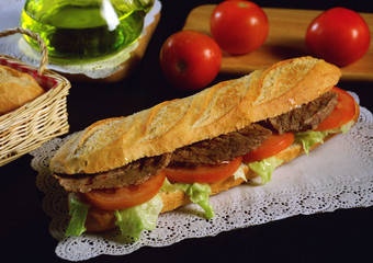 Un bocadillo con una baguette, ensalada de lechuga y tomate y biftec de ternera a la plancha. 