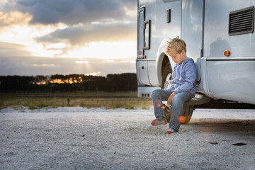 Young boy sitting outside his motor home at sunset