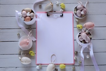 Easter Flat lay. Spring Easter Mockup.Decorative eggs, blank notepad  on gray wooden  background.