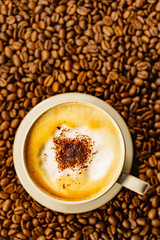Cappuccino cup on roasted coffee beans.