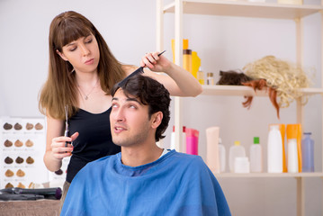 Obraz na płótnie Canvas Young attracrive man visiting female barber 