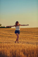 Cute young woman jumping in a wheat field.