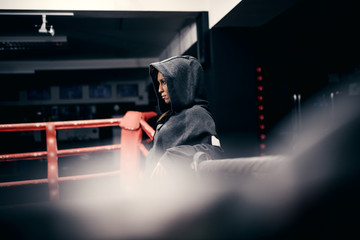 Badass powerful caucasian female boxer posing in ring with hoodie on head.