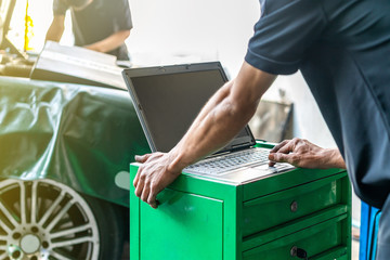 Close up hand finger of repairman touch laptop or computer notebook interfaced with car for repair during work investigate problem (program and electric check) automobile gasoline or diesel engine