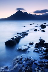 Waves crashing on shoreline with moody dramatic sky at Elgol on the Isle of Skye, Scotland, UK. The famous rocky bay. The Cuillins mountain in the background. Beautiful sunset background concept 