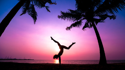 Beautiful young woman practic yoga at the beach. Early morning exercise. Sunrise