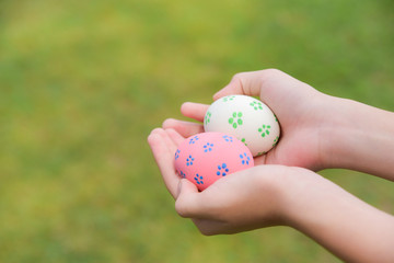 Happy Easter Day. Easter eggs concept. Colorful easter eggs in children hands after egg hunting on green grass background.