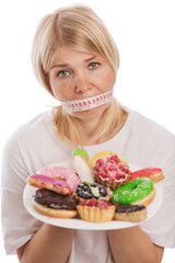 Young woman with mouth bent with a plate of cakes, isolated on white background