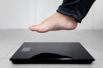 Obese man feet step on the weighing scale