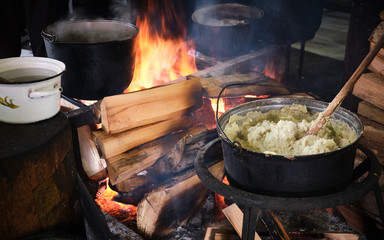 Traditional georgian food, hominy (mamaliga) is cooked in the large cooking pot on fire