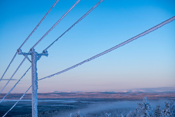 Frost and snow covered power lines during very cold winter against sky