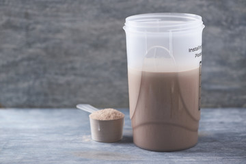 Whey protein shaker and scoop. Sport nutrition. Rustic wooden background. Copy space. 