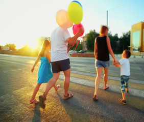 Fototapeta premium Abstract, blur background, defocusing - image for the background. Happy family playing with balloons on the road in the sunset time.