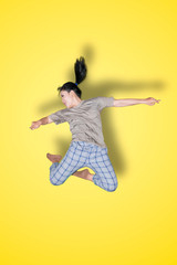 Obraz premium Young Asian woman performs jump in the studio