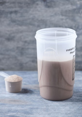 Whey protein shaker and scoop. Sport nutrition. Rustic wooden background. Copy space. 