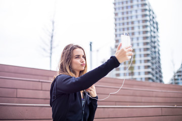 Young  fit sporty woman and listen to music and taking selfie on mobile phone and resting after  training