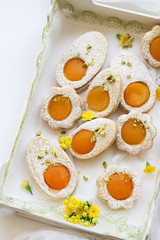 Cookies in the shape of white eggs with apricot yolk with pistachios as homemade decoration