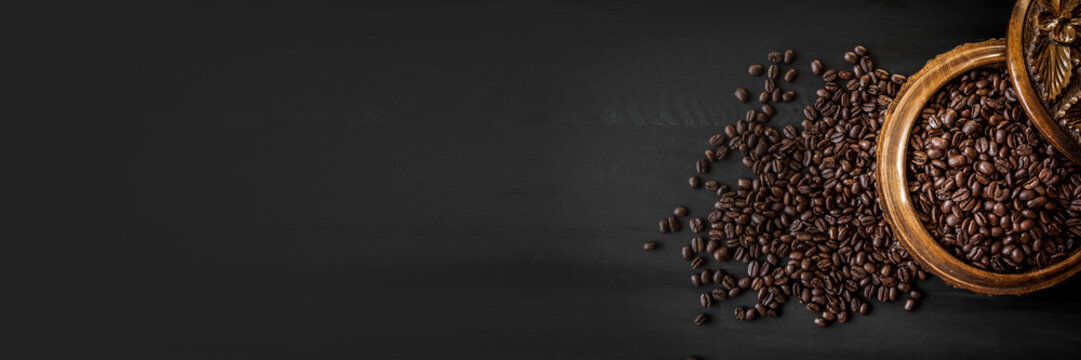 Fresh roasted arabica and robusta coffee beans. Coffee in a wooden bowl on a dark wood background Banner