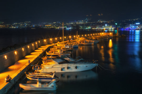 Night view of the pier in Chersonissos. Sea vessels moored at the pier.