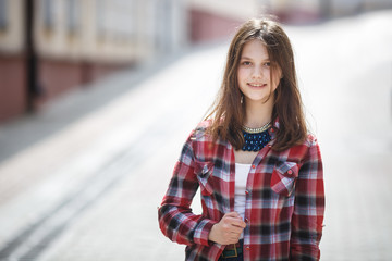 Fototapeta na wymiar close up portrait of beautiful girl teenager in bright plaid shirt in urban street background