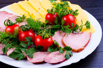 Sausage and meat with cheese and herbs in a light bowl on a dark background.