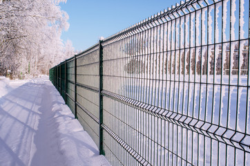 The metal fence in the winter Park is depicted in a sharp perspective, occupies half of the image field, close-up, instagram.