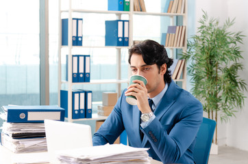 Young handsome male employee with too much work in the office  