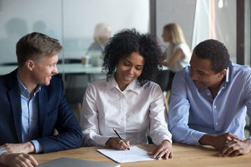 Black confident woman sitting with business partners signing contract 