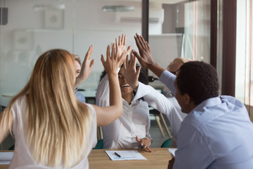 Like minded diverse teammates giving high five celebrating success 