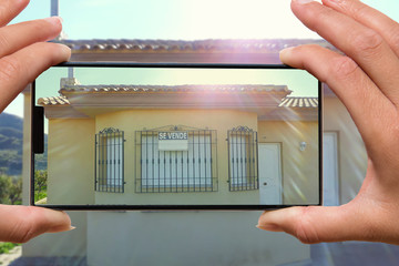 Female hands photographing on cellphone house for sale spanish se vende