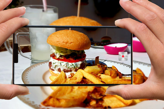 woman photographing on cell phone homemade hamburger and fries