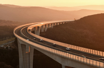 Cars driving on a highway viaduct at sunset