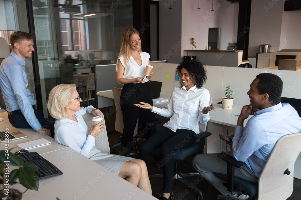 Wall mural Workmates take a break during workday drinking coffee and chatting