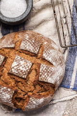 Freshly baked round bread on wheat sourdough and mortar with salt on a  linen towel, close-up. Sourdough bread recipe