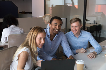 Three cheerful employees working at coworking room using computer