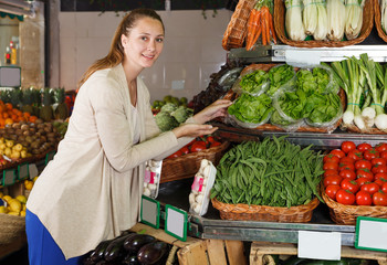 Glad woman is choosing fruits and vegetables