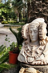 Lady of Elche bust in a garden under the sun