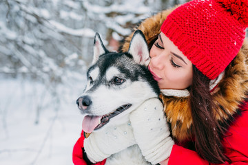 Woman caresses the Husky dog in winter forest