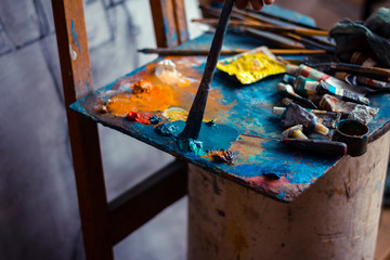 Cropped image of artist taking paint from palette in workshop