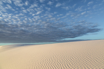 Fototapeta na wymiar Clouds over the sand dunes at sunrise, at White Sands National Monument, New Mexico
