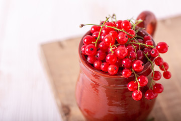 Fresh red currant in a ceramic cup on a white wooden background