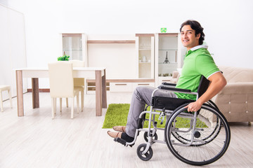 Young handsome man in wheelchair at home 