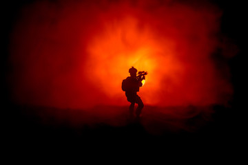 Naklejka na ściany i meble Military soldier silhouette with gun. War Concept. Military silhouettes fighting scene on war fog sky background, World War Soldier Silhouette Below Cloudy Skyline At night.